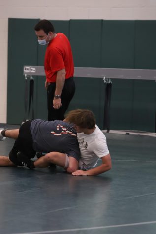 Wrestling Coach Nick Adamson coaches members of the wrestling team at a pre-season practice. “A lot of what this year is going to be about is restarting and rekindling the program to remind people what it was and get them back on board, Adamson said.