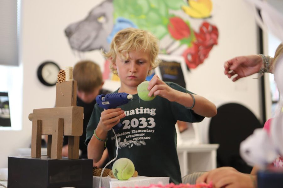 Dylan Compton glues tennis balls together to form scales for his sculpture of a fish. Sculpture Evergreen provided kids with recycled materials to create their own sculptures