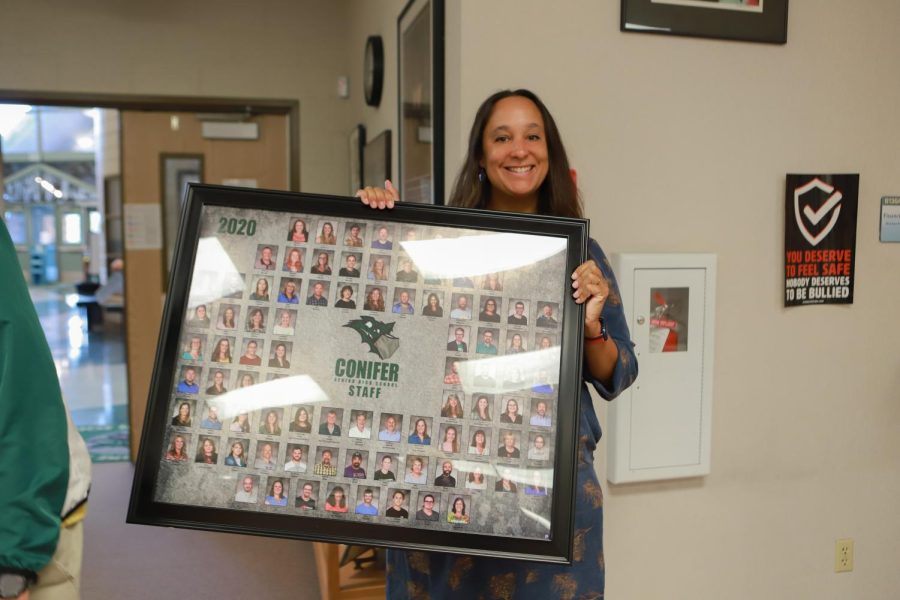 Ms. Paschke standing in the main office holding the staff photos.