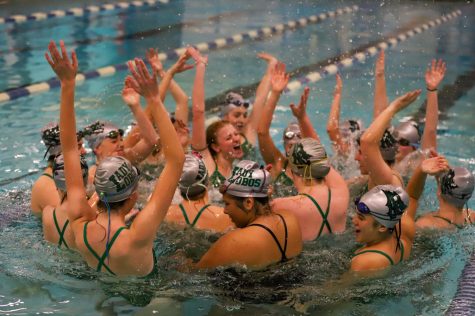 The 2021-2022 swim team celebrates in the pool together after a meet.