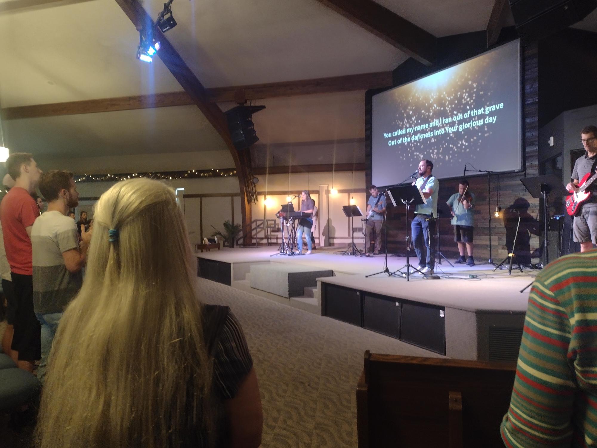 Pictured above is a worship group performing on stage at Lakewood Vineyard Church. Worship groups are religious teams that perform Christian music, starting and ending Christian services. The words are typically projected on screen so attendees can sing along.