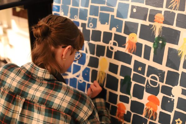 Sophomore NAHS Member Enji Jensen paints the senior mural. This year’s senior mural is an underwater theme, featuring jellyfish, whales, bubbles, and other underwater creatures. Seniors’ fingerprints are meant to resemble fish, forming a school of fish following the large whales. “It takes a lot of people and a lot of planning,” Enji said.
