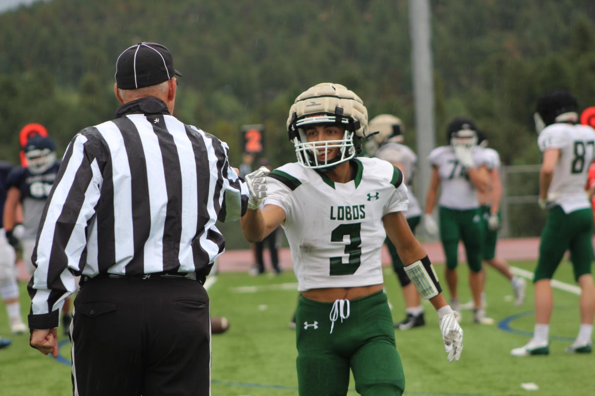 Senior Mason Murphy fist-bumps the referee during the varsity scrimmage against Palmer Ridge High School on August 22nd. Coach Matthew Steinfeltt used this opportunity with his team to practice their plays and prepare for their upcoming season. “After the scrimmage against Palmer Ridge, I’m confident in the upcoming season. I think we are already improving and might even make playoffs this year,” senior Teddy Arnold said. 