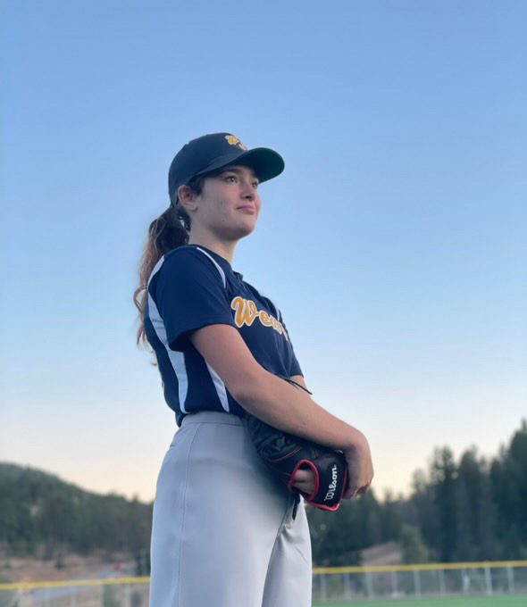 Emerson Brooks poses on the baseball field in her West Jefferson jersey and glove. West Jefferson Baseball was founded in 1984 and has had around 5,000+ players through its program. This competitive program is meant for girls and boys ages 8-14 and is where many Conifer players start their baseball careers. Brooks is the first female on the Conifer High School Baseball team and played on this league growing up. “One thing my mom tells me is that if anyone ever looks at you weird for what you’re doing, remember that you're accomplishing your goals and it shows your confidence,” Brooks said. (Provided by Emerson Brooks)
