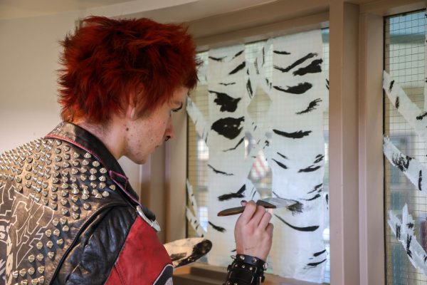 Senior Garrison (Max) Gibson paints aspen trees in the library windows. To share his creativity and bring more color to the halls, the library asked Gibson to paint the windows with something that represented Conifer. "I love my art, I love having it up. Being able to walk down my hallways in my school and see that, that feeling  just makes me so happy," GIbson said.
